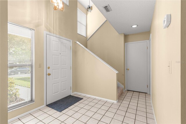 foyer entrance with a textured ceiling and light tile patterned flooring