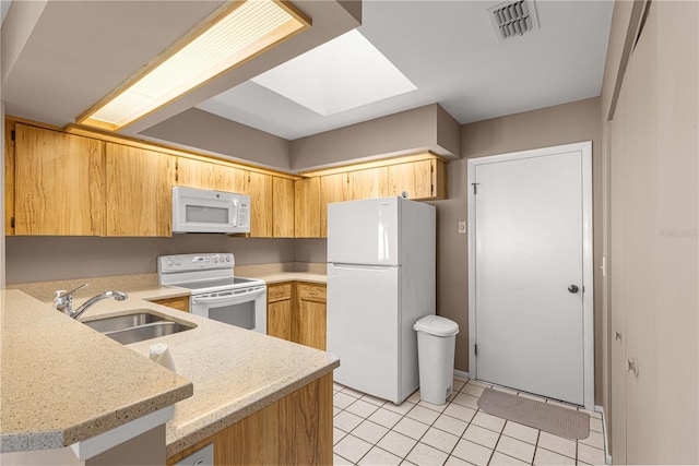 kitchen with white appliances, sink, a skylight, light tile patterned flooring, and kitchen peninsula