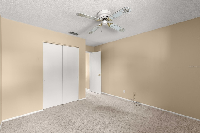 unfurnished bedroom featuring a textured ceiling, a closet, ceiling fan, and light colored carpet