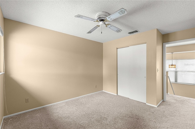 unfurnished bedroom featuring carpet flooring, a textured ceiling, a closet, and ceiling fan