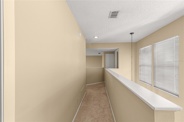 hallway featuring a textured ceiling and light colored carpet