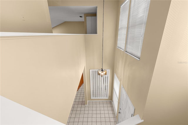 staircase featuring tile patterned flooring and a chandelier