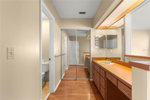 bathroom featuring hardwood / wood-style flooring, vanity, and toilet