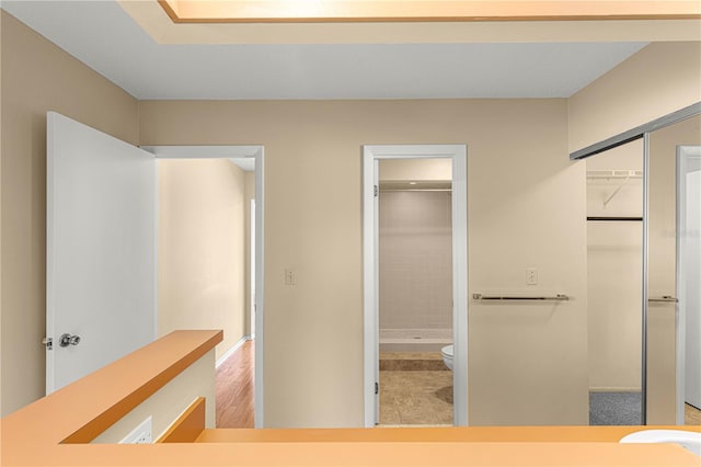 bathroom with tiled shower, hardwood / wood-style floors, and toilet