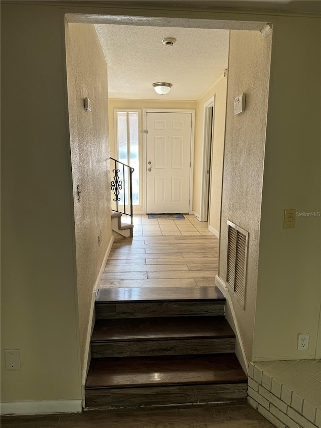 stairs featuring hardwood / wood-style floors and a textured ceiling