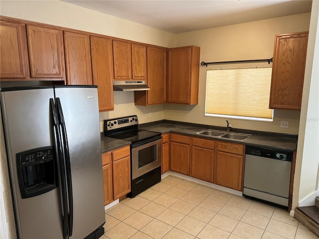 507 NW 39th Rd Unit 159, Gainesville, FL 32607 - kitchen featuring stainless steel appliances, under cabinet range hood, dark countertops, brown cabinetry, and light tile patterned floors