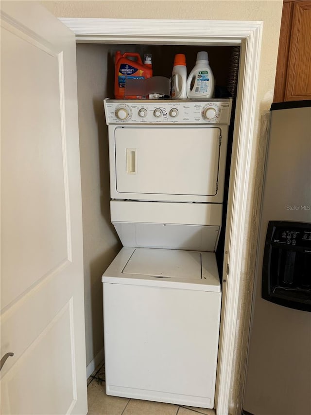 clothes washing area with light tile patterned floors and stacked washer / drying machine