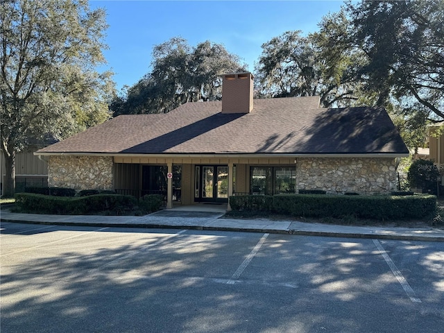 507 NW 39th Rd Unit 159, Gainesville, FL 32607 - view of front of house featuring stone siding, a chimney, uncovered parking, and a shingled roof