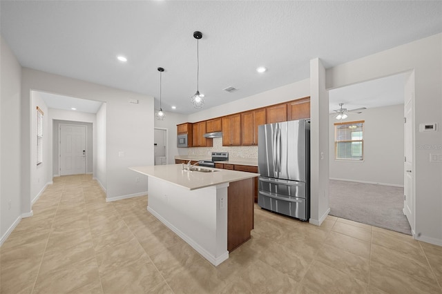 kitchen featuring ceiling fan, sink, hanging light fixtures, a kitchen island with sink, and appliances with stainless steel finishes