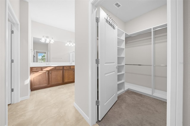 walk in closet with sink and light colored carpet