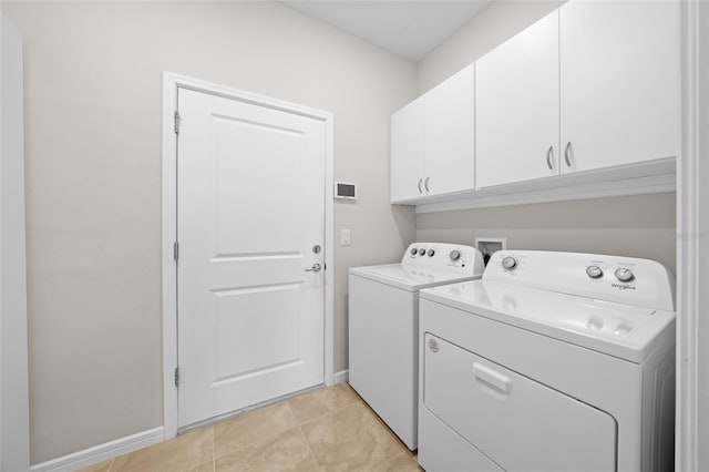 clothes washing area featuring washer and dryer, cabinets, and light tile patterned flooring