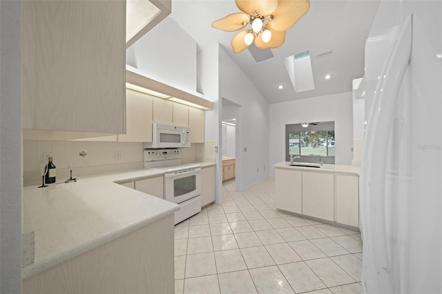 kitchen featuring a skylight, light countertops, backsplash, light tile patterned flooring, and white appliances