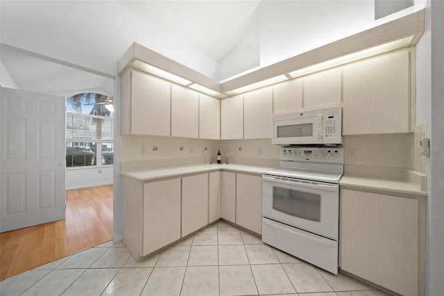 kitchen featuring vaulted ceiling, light countertops, white appliances, and backsplash