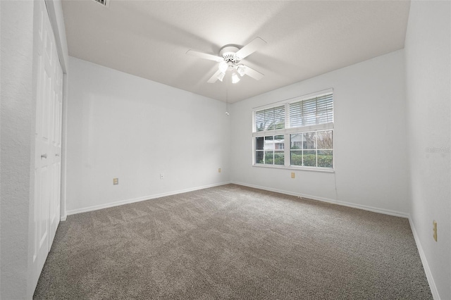 carpeted spare room with a ceiling fan and baseboards