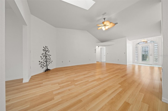 unfurnished living room featuring light wood-style floors, vaulted ceiling with skylight, baseboards, and ceiling fan with notable chandelier