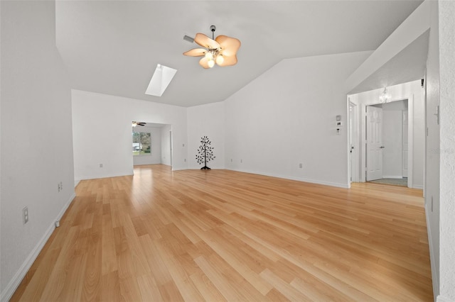 unfurnished living room featuring lofted ceiling with skylight, ceiling fan, light wood-style flooring, and baseboards