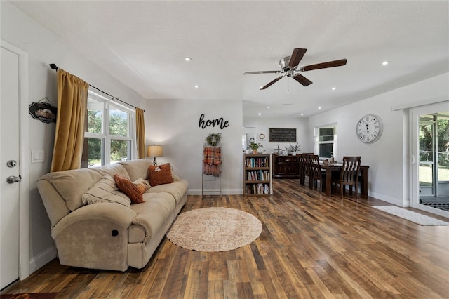 living room featuring ceiling fan and dark wood-type flooring