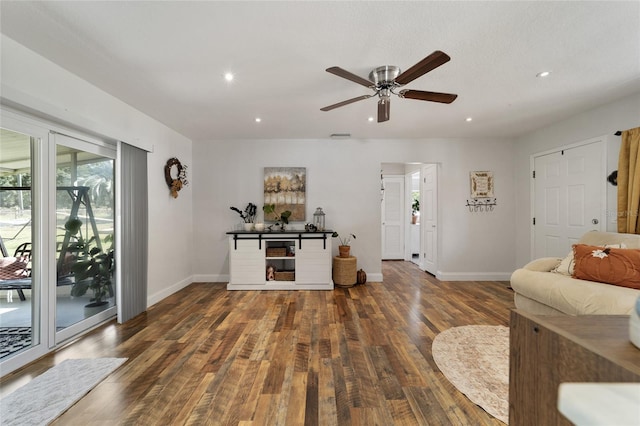 living room with a textured ceiling, ceiling fan, and dark hardwood / wood-style floors