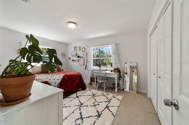 bedroom with light colored carpet, a textured ceiling, and a closet