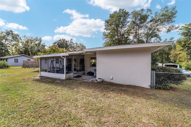 rear view of property with a lawn and a sunroom