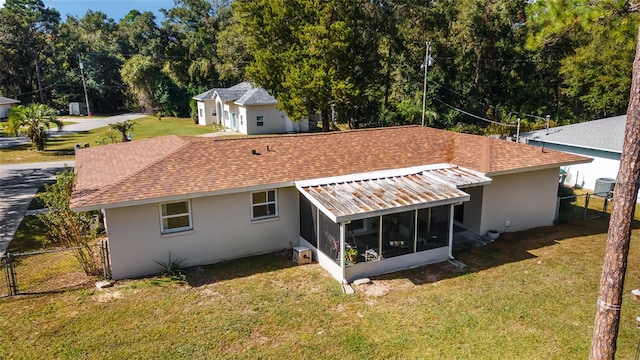 rear view of property featuring a sunroom and a lawn