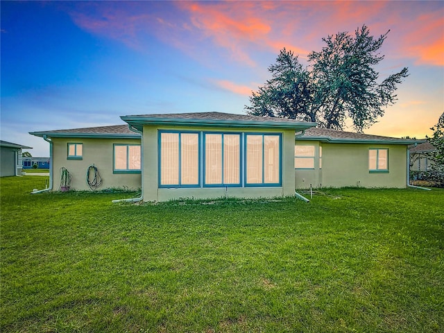 back house at dusk featuring a yard