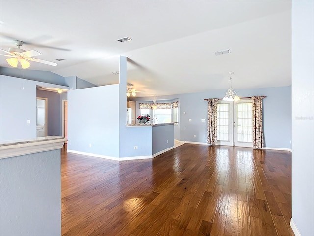 unfurnished living room featuring hardwood / wood-style flooring, ceiling fan with notable chandelier, lofted ceiling, and french doors