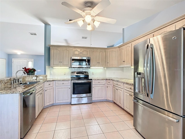 kitchen featuring ceiling fan, sink, light stone counters, kitchen peninsula, and appliances with stainless steel finishes