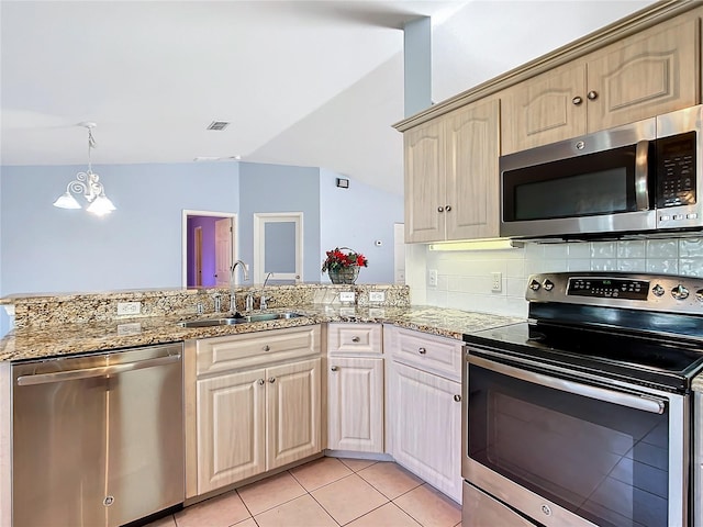 kitchen with sink, a chandelier, vaulted ceiling, light tile patterned floors, and appliances with stainless steel finishes