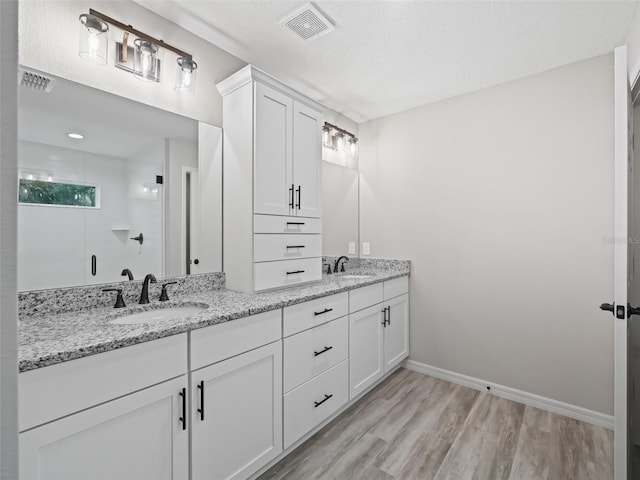 bathroom featuring vanity, hardwood / wood-style floors, a textured ceiling, and walk in shower