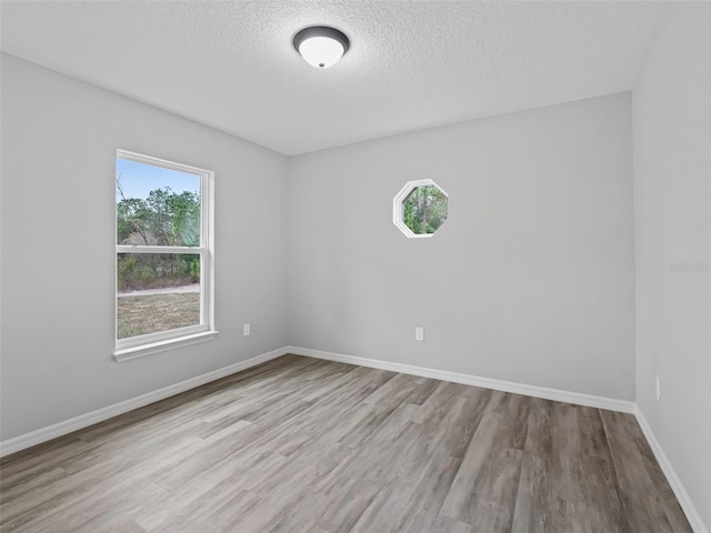 empty room with a textured ceiling and light wood-type flooring