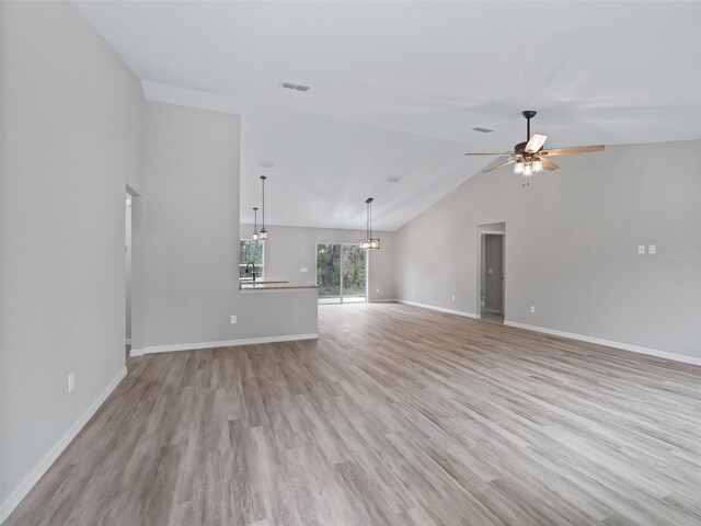 unfurnished living room featuring ceiling fan, sink, light hardwood / wood-style floors, and lofted ceiling