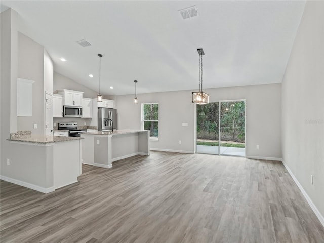 kitchen with appliances with stainless steel finishes, vaulted ceiling, decorative light fixtures, light hardwood / wood-style flooring, and white cabinets