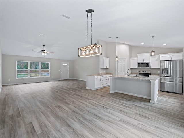 kitchen with white cabinets, hanging light fixtures, lofted ceiling, and appliances with stainless steel finishes