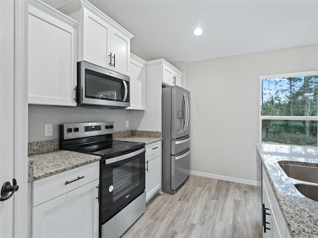 kitchen featuring white cabinets, light stone counters, light wood-type flooring, and appliances with stainless steel finishes