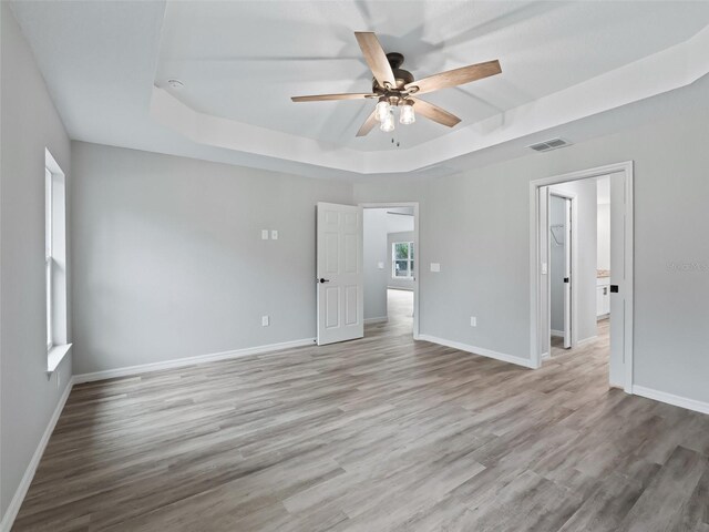 spare room featuring ceiling fan, a tray ceiling, and light hardwood / wood-style flooring