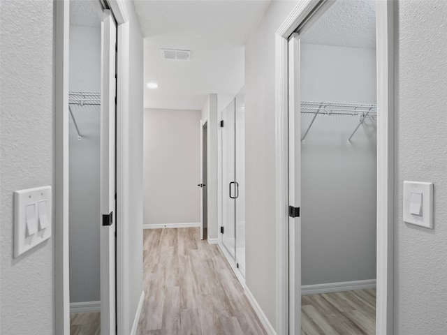 hallway featuring a textured ceiling and light hardwood / wood-style flooring