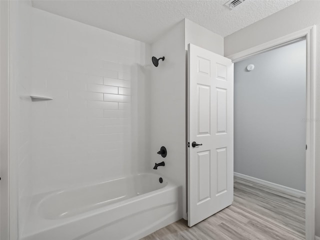 bathroom with a textured ceiling, bathtub / shower combination, and hardwood / wood-style flooring