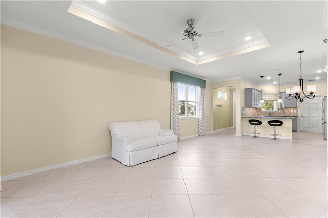 living area featuring light tile patterned floors, ceiling fan with notable chandelier, a raised ceiling, and crown molding