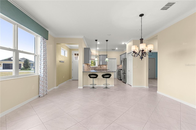 kitchen with gray cabinetry, stainless steel appliances, an inviting chandelier, a kitchen breakfast bar, and crown molding