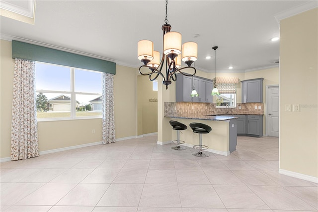 kitchen featuring hanging light fixtures, a chandelier, gray cabinets, decorative backsplash, and ornamental molding