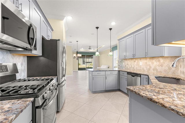 kitchen with appliances with stainless steel finishes, dark stone counters, crown molding, sink, and pendant lighting