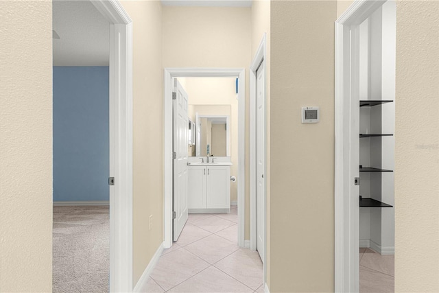 hall with sink and light tile patterned flooring