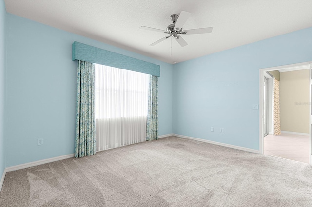 empty room featuring ceiling fan, light colored carpet, and a textured ceiling