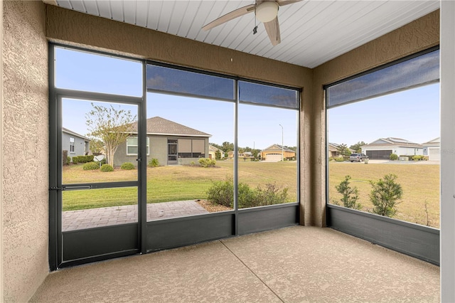 unfurnished sunroom featuring ceiling fan and a healthy amount of sunlight