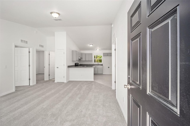 unfurnished living room with light colored carpet, sink, and high vaulted ceiling