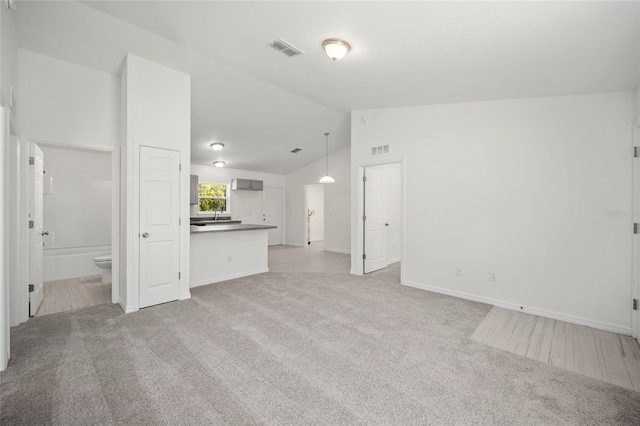 unfurnished living room featuring light carpet and high vaulted ceiling