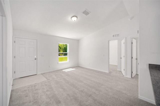 unfurnished room featuring light colored carpet and vaulted ceiling