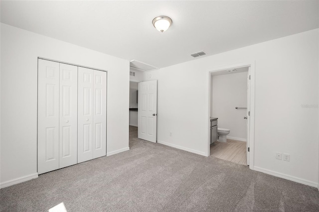 unfurnished bedroom with ensuite bathroom, light colored carpet, and a closet