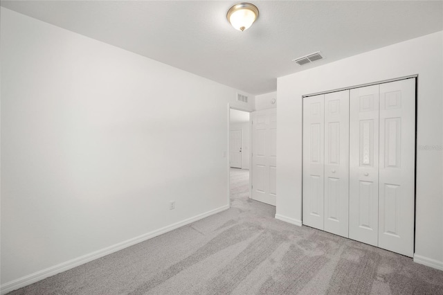 unfurnished bedroom with light colored carpet and a closet